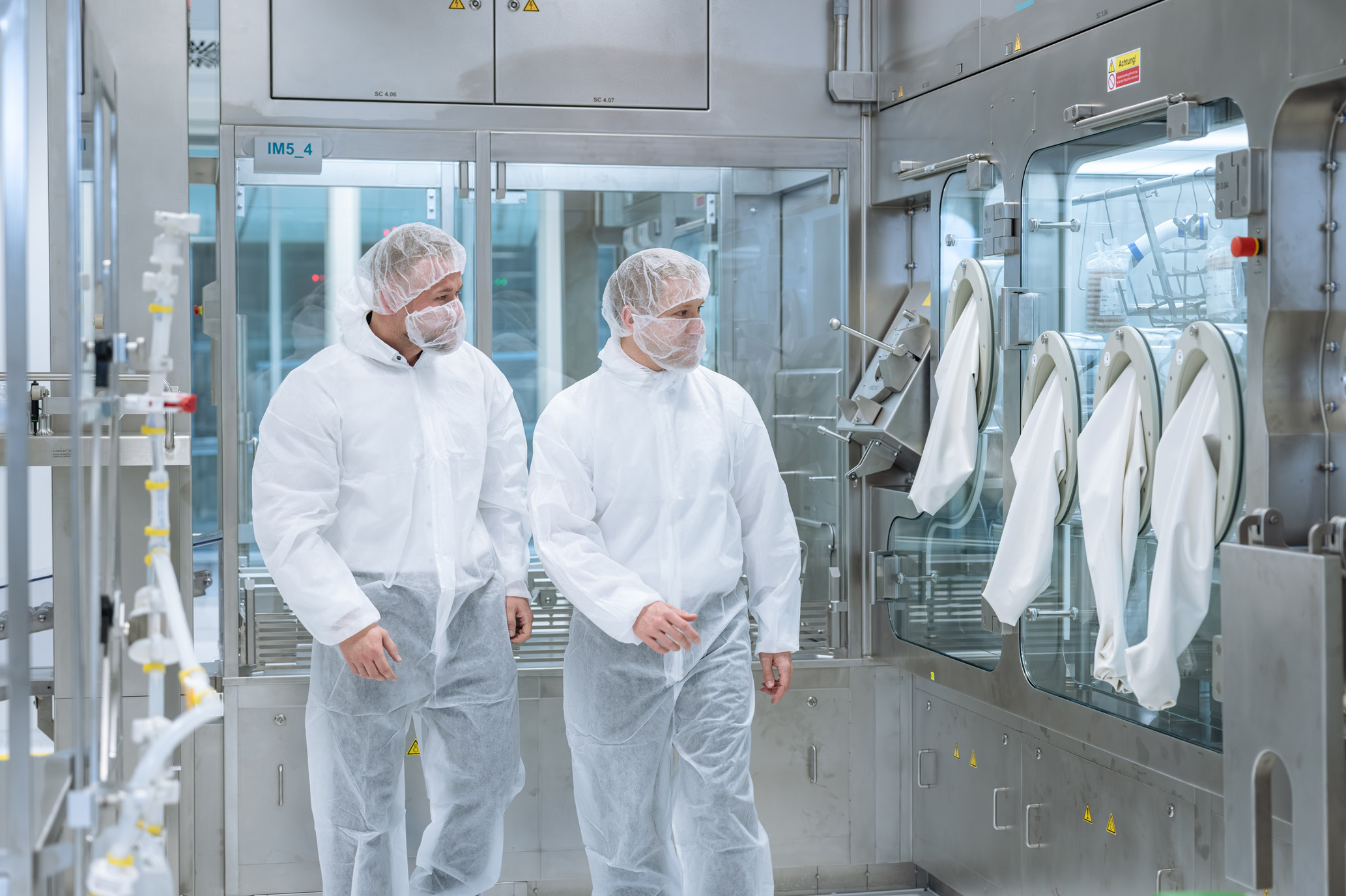 A group of seven people in full cleanroom protective clothing and blue shoe covers