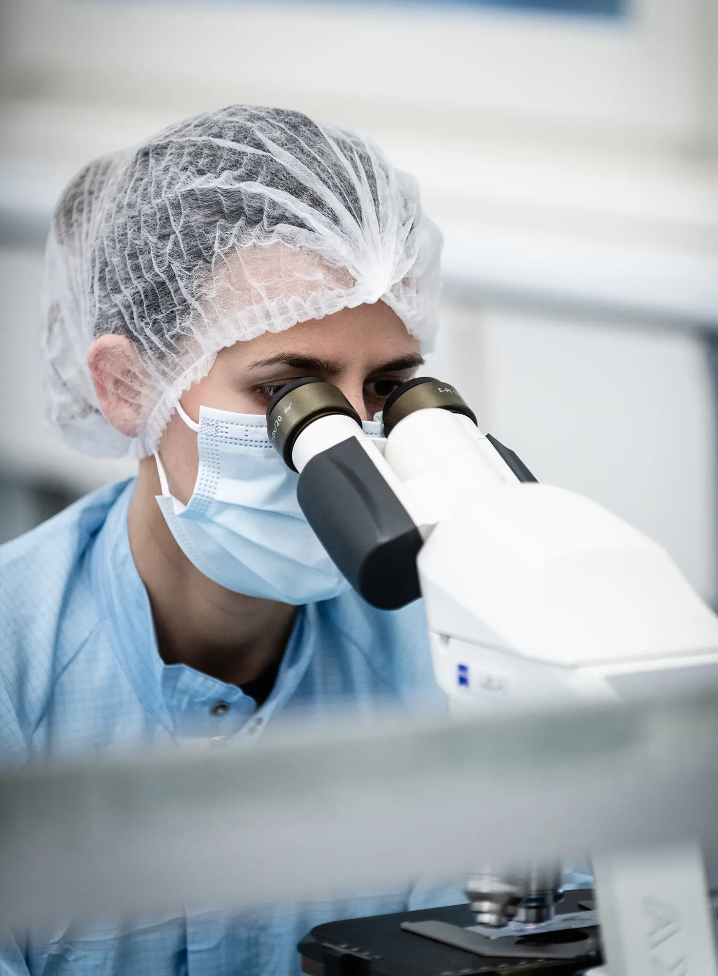Lab technician looks through a microscope